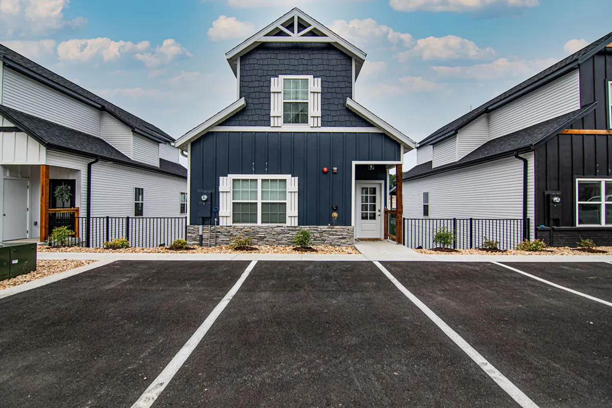 The front entrance of the house is shown, featuring unique architectural elements and a landscaped area. The setting feels inviting, signaling the start of an adventure and offering plenty of room for outdoor activities and family gatherings.